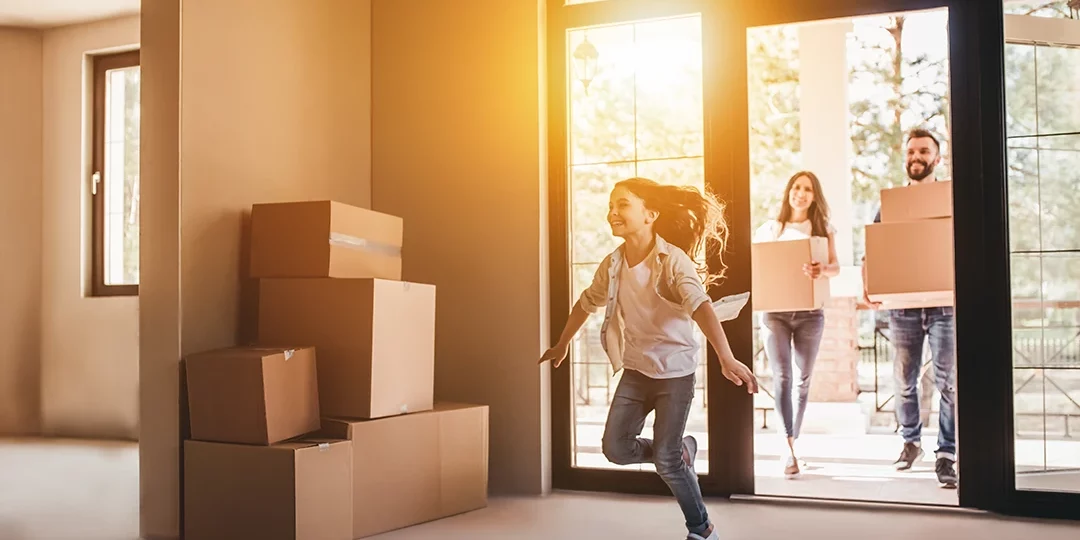 Family walking into new home with moving boxes.