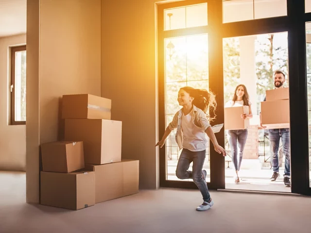 Family walking into new home with moving boxes.
