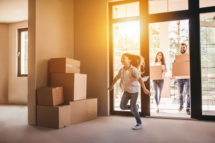Family walking into new home with moving boxes.